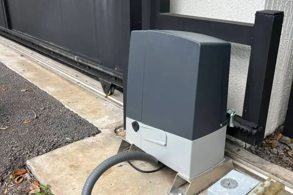 Gray slide gate operator beside a black driveway gate
