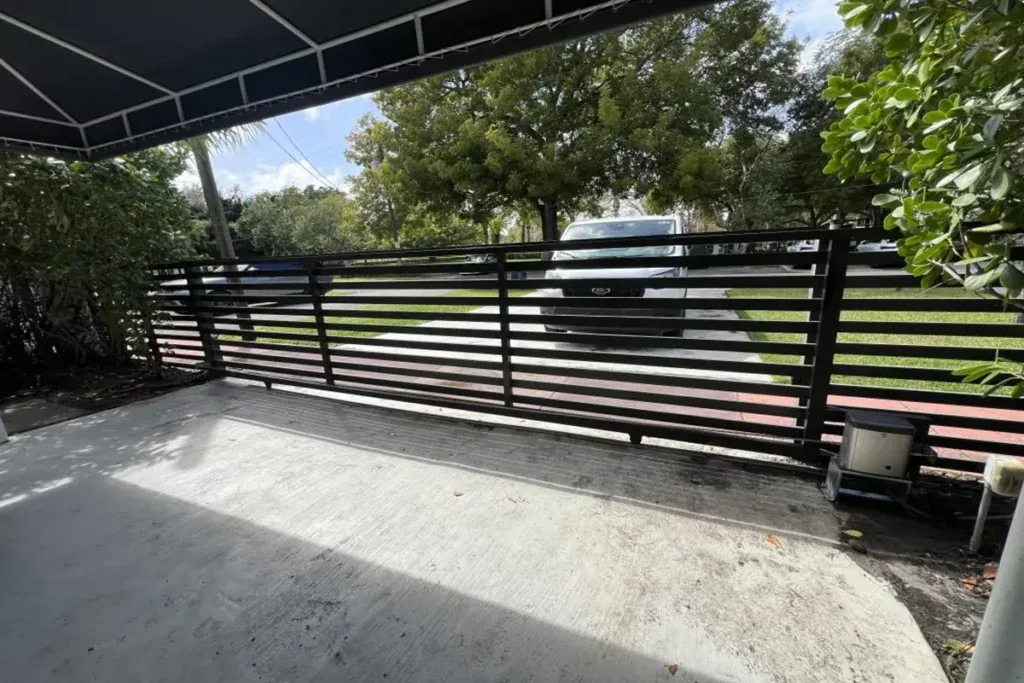 Slide gate operator mounted beside a metal driveway gate