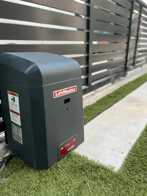 LiftMaster slide gate opener beside a horizontal-slat aluminum gate