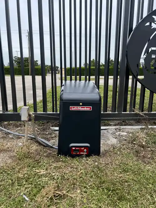 LiftMaster slide gate operator at the base of a black metal fence